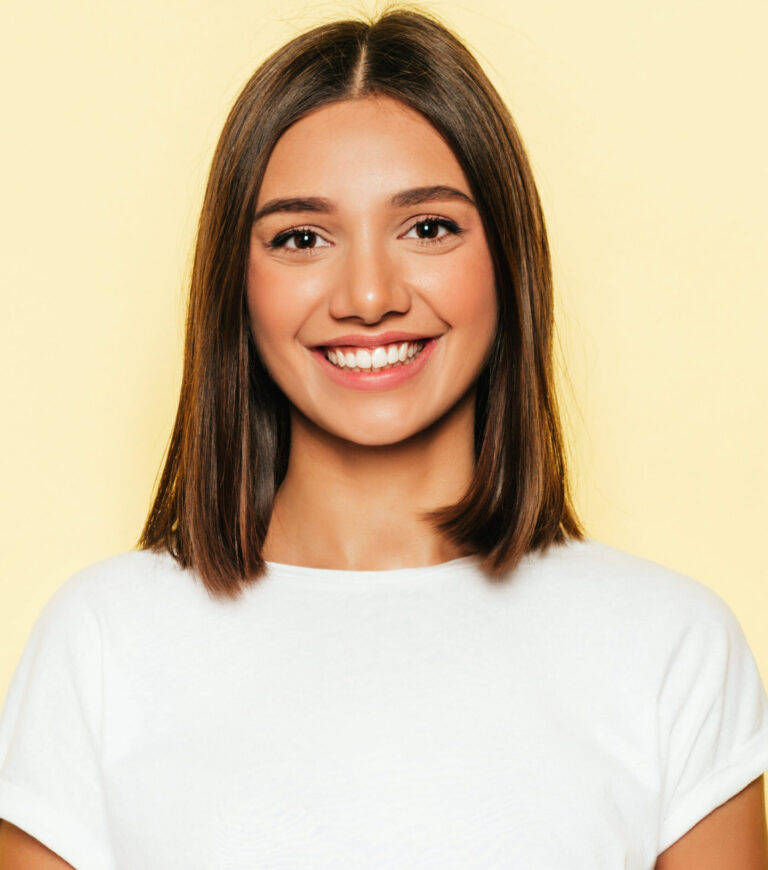 Young beautiful woman looking at camera.Trendy girl in casual summer white T-shirt and jeans shorts.Positive female shows facial emotions