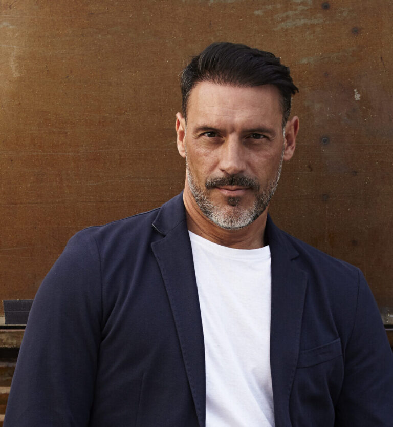 middle-aged-man-wearing-leaning-against-rusty-colored-background-scaled-e1761567565561